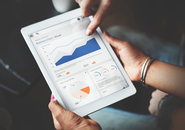Mains utilisant une tablette affichant des statistiques de données commerciales pour la personnalisation de l'expérience client.